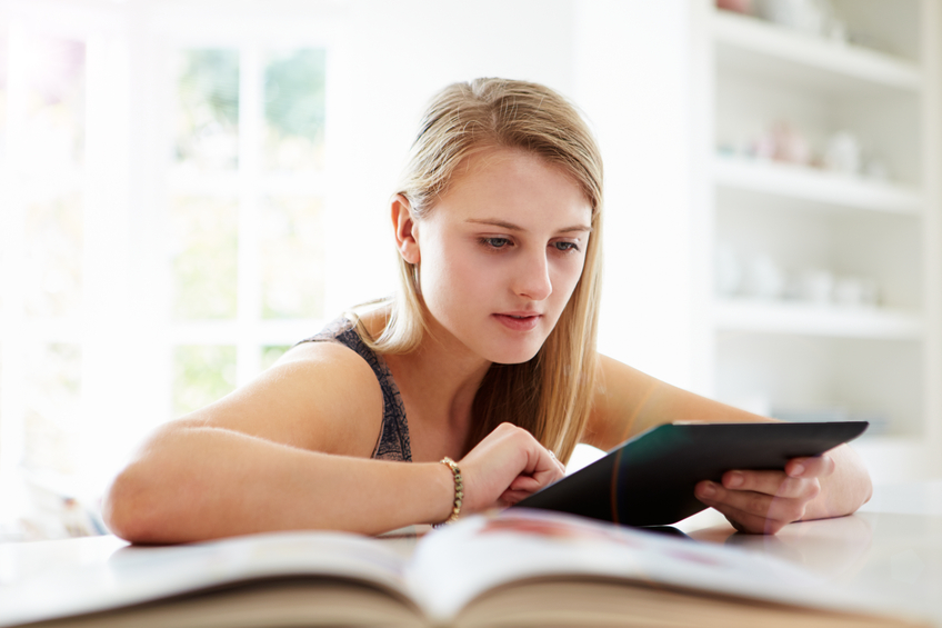 Teenage Girl Studying Using Digital Tablet At Home